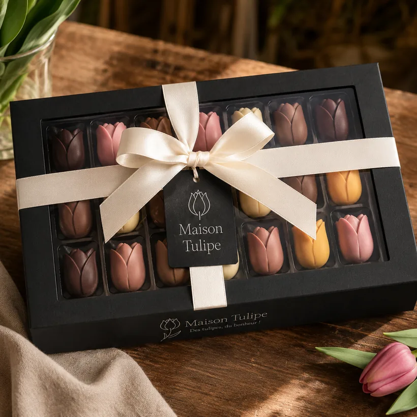 Coffret noir mat de chocolats tulipe fermé par un ruban crème.